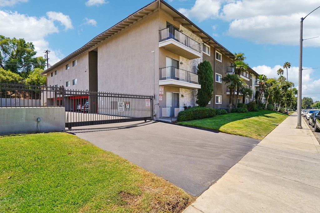 a white apartment building with a sidewalk and grass