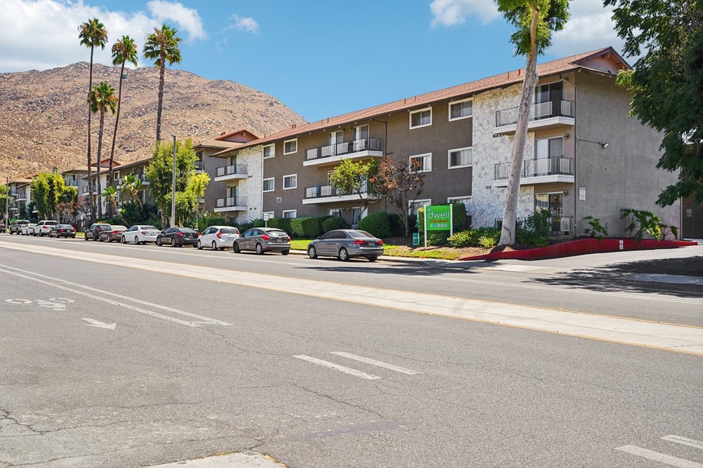a city street with cars parked in front of an apartment building