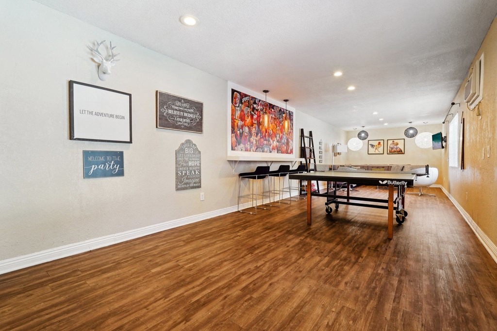a game room with a ping pong table and paintings on the wall