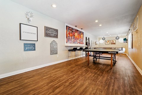 a game room with a ping pong table and paintings on the wall