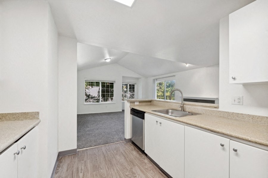 a kitchen with white cabinets and a sink and a window