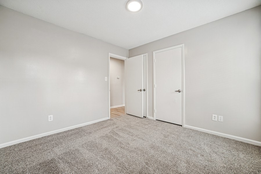 A room with a carpeted floor and three doors.