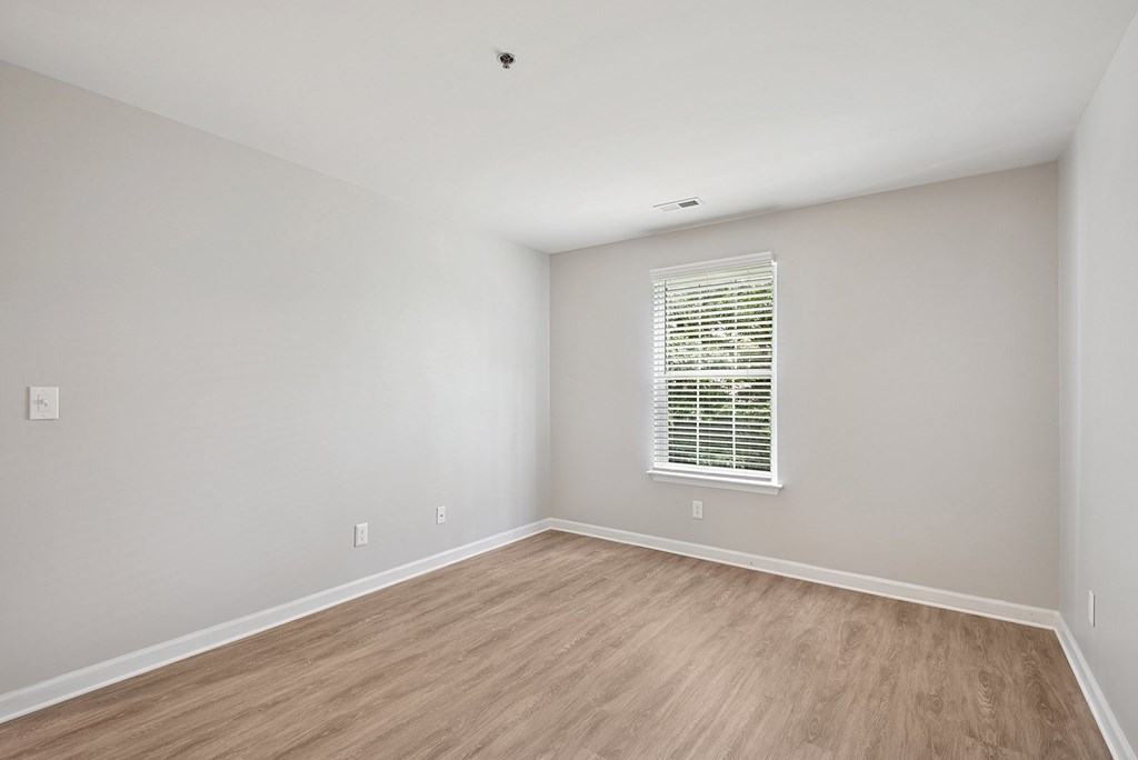 A room with a window and wooden flooring.