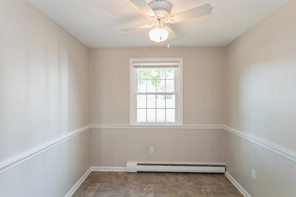 Empty carpeted room with ceiling fan and window