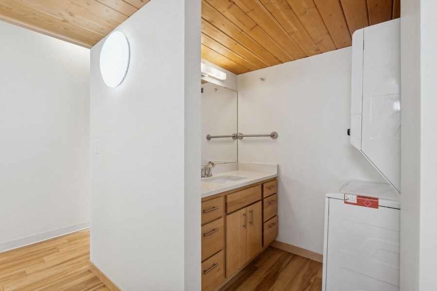 A small bathroom with a wooden floor and white walls.