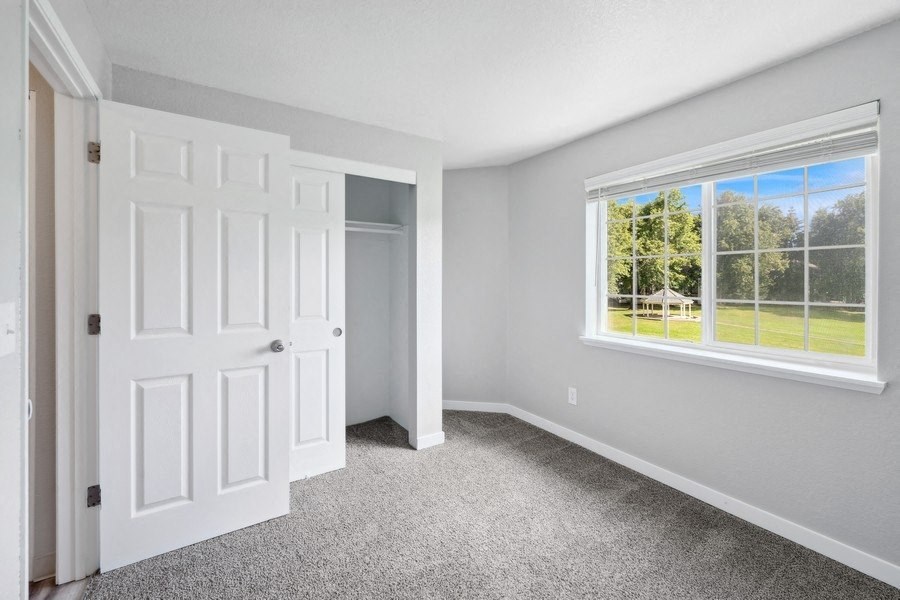 a bedroom with a large window and a carpet floor at Sundial Apartments, Wilsonvile, Oregon