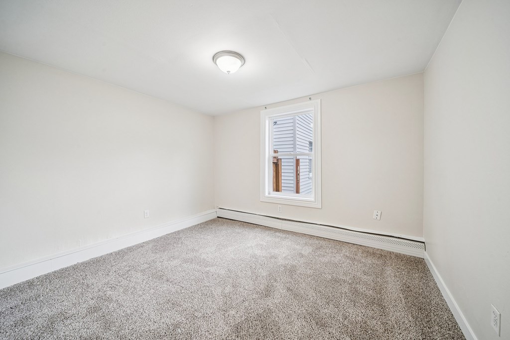 A room with a carpeted floor and a window with blinds.
