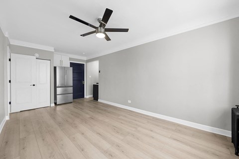 A room with a ceiling fan and light, hardwood floors, and a white door at Pleasant Oak Apartments, Illinois, 60302