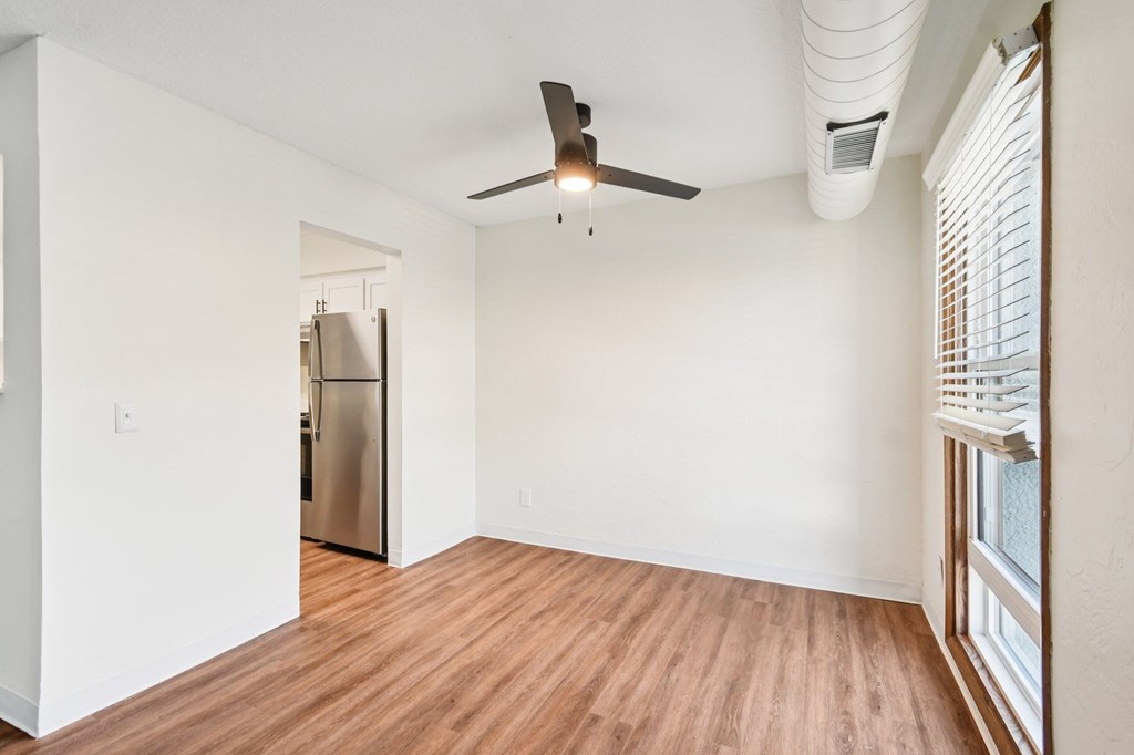 A room with a ceiling fan and wooden flooring.
