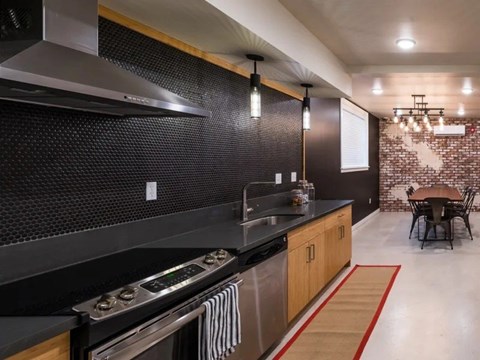 A modern kitchen with a stove top oven and a black counter top.