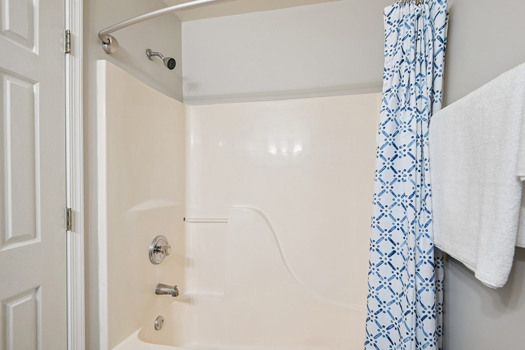 A white bathroom with a blue and white shower curtain.