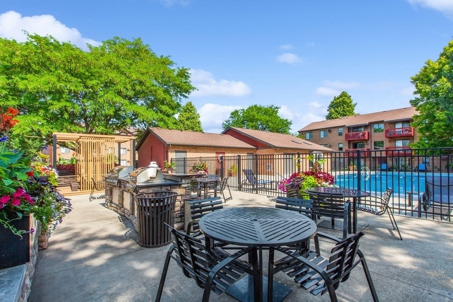 a patio with tables and chairs and a pool in the background