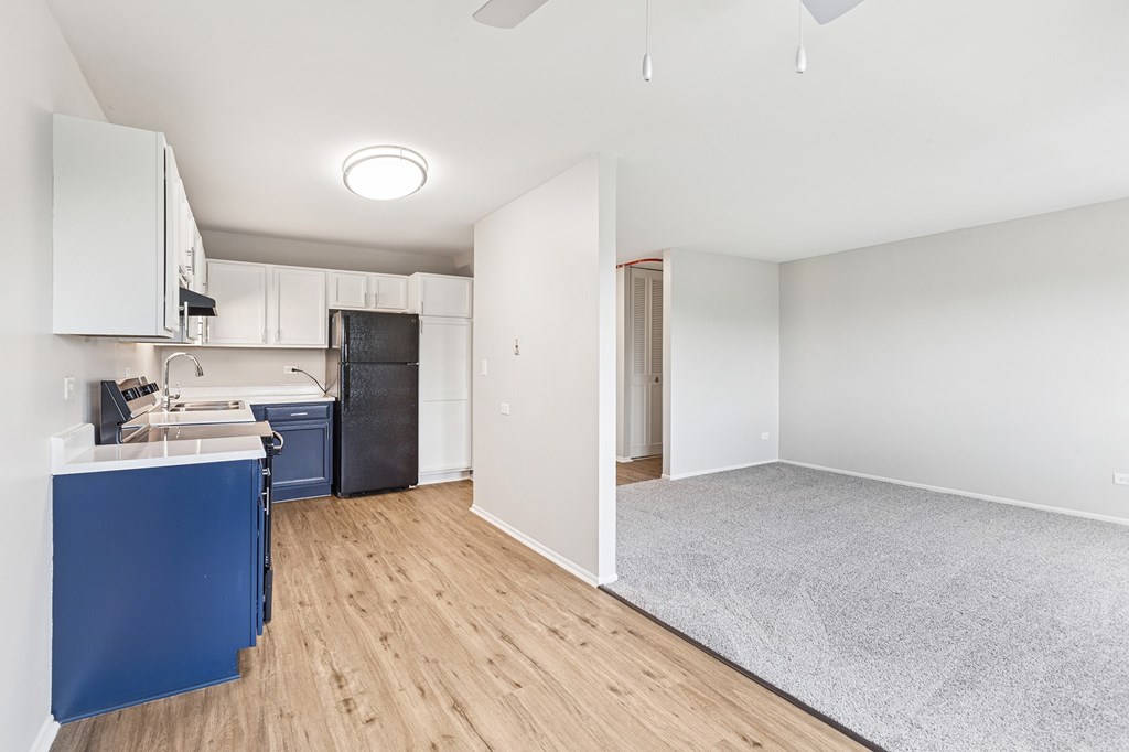 A kitchen with white cabinets and a wooden floor.