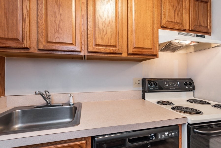 A kitchen with wooden cabinets and a stove top oven.
