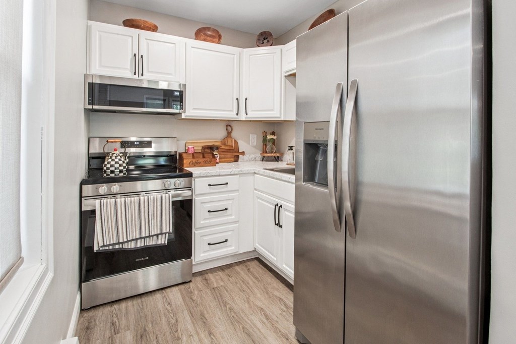 A modern kitchen with a stainless steel refrigerator and white cabinets.