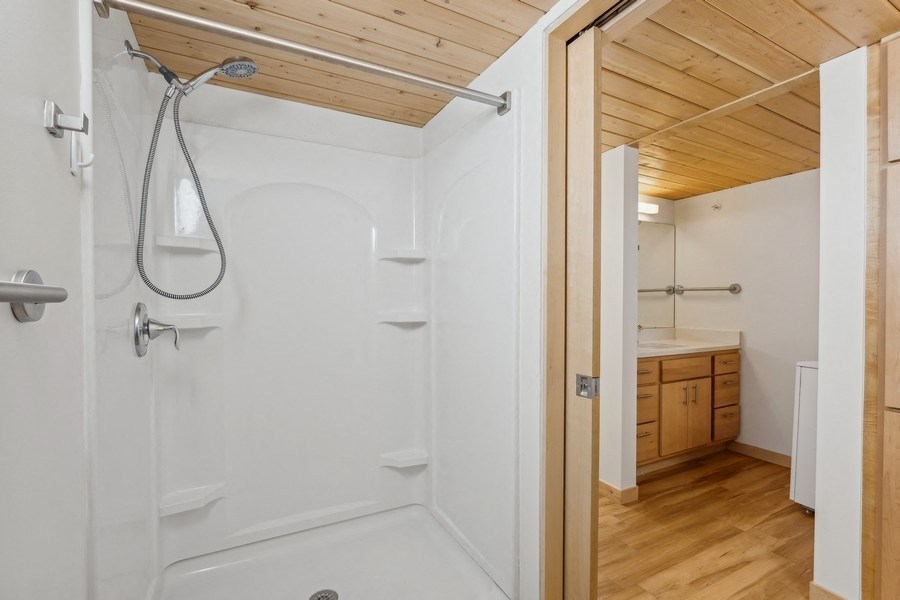 A white bathroom with wooden ceiling and floor.