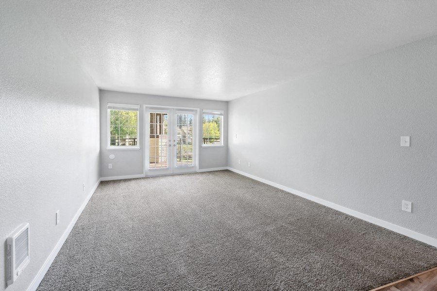 an empty living room with a door to a patio at Sundial Apartments, Wilsonvile, Oregon