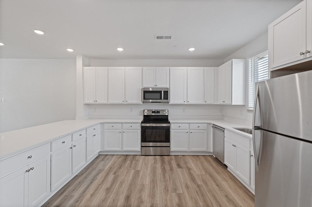 a large white kitchen with white cabinets and a stainless steel refrigerator