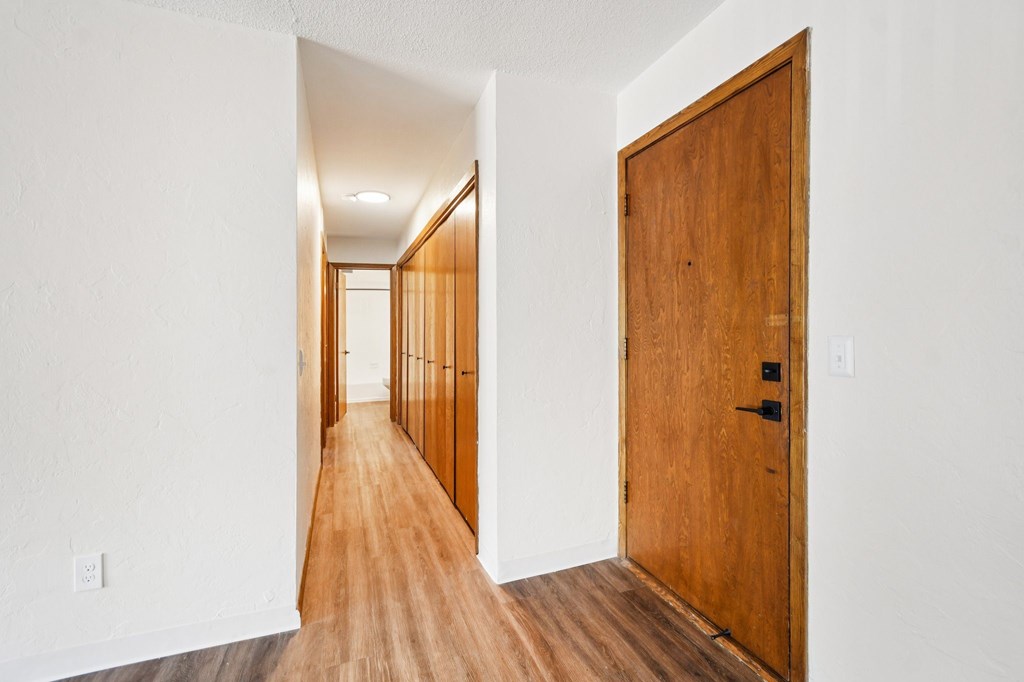 A long hallway with a wooden floor and white walls.