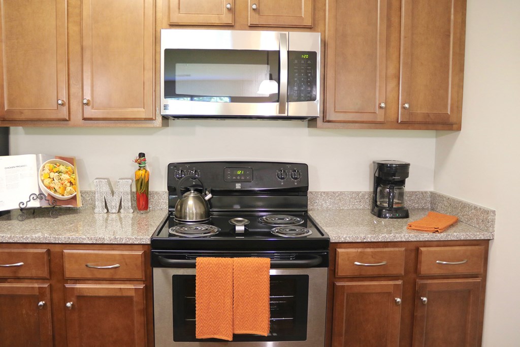 a kitchen with a stove and microwave and wooden cabinets