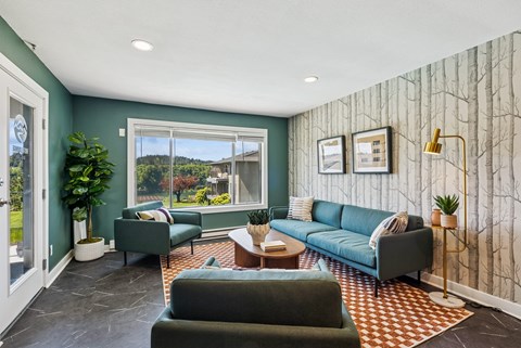 A living room with a green couch and a grey armchair.
