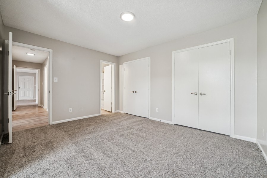 A spacious room with white doors and carpeted floor.
