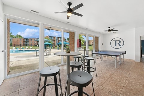 A room with a pool outside the window and a table with chairs.