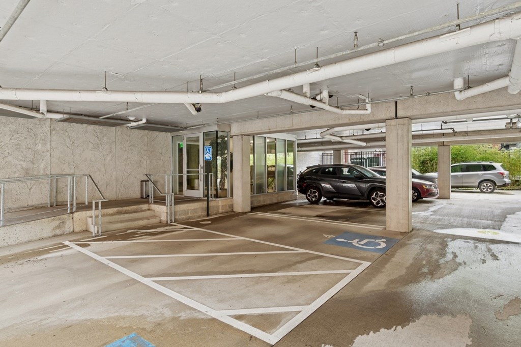 A parking garage with a car parked in a handicapped spot.