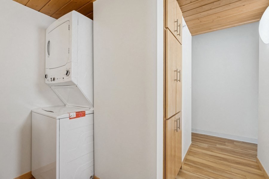 A white fridge and freezer in a kitchen with wooden floors and cabinets.