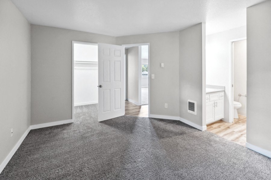 an empty  room with a carpeted floor and a door to a bathroom at Sundial Apartments, Wilsonvile, Oregon