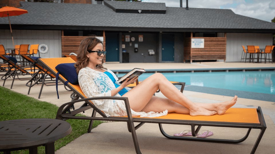 a woman sitting on a chaise lounge by a pool with a tablet in her hand at The Township at St. Charles, Illinois, 60174