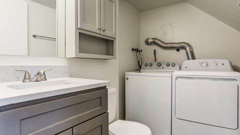a white washer and dryer in a kitchen with a sink and washing machine