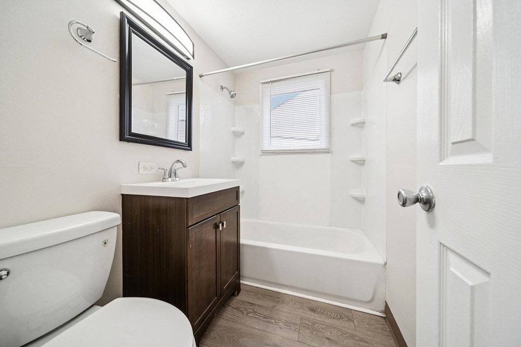 A white bathroom with a white toilet and a white bathtub.