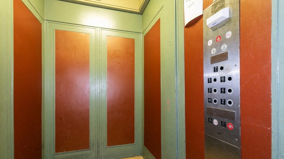 a row of elevators in a building with red doors