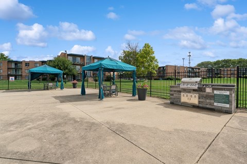 A playground with a green canopy and a sign on a wooden post.