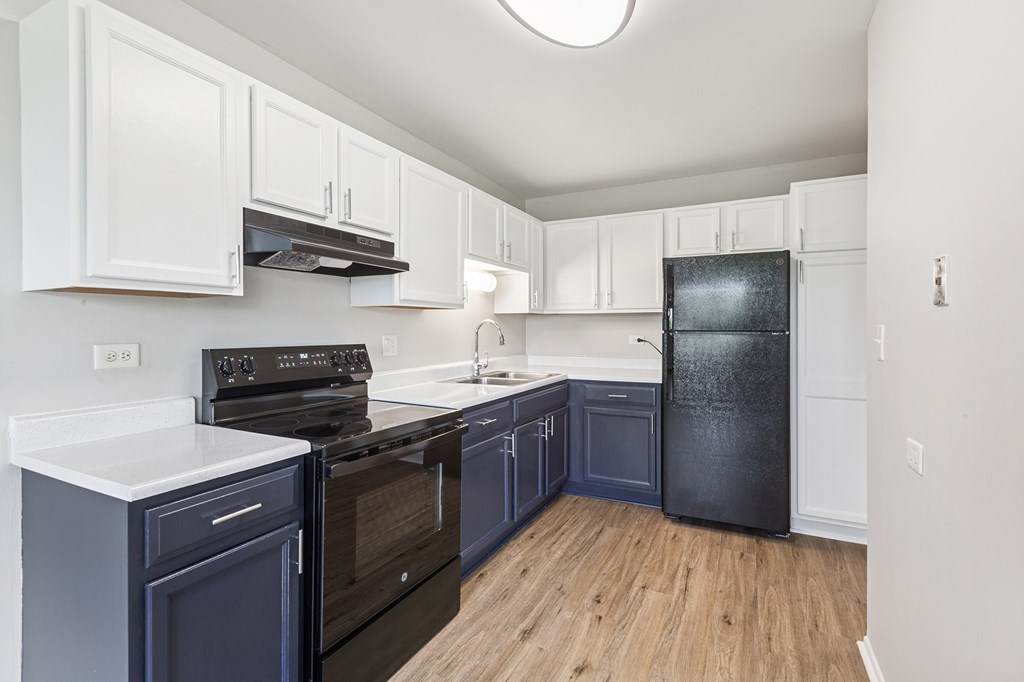 A kitchen with white and blue cabinets and a black stove top oven.