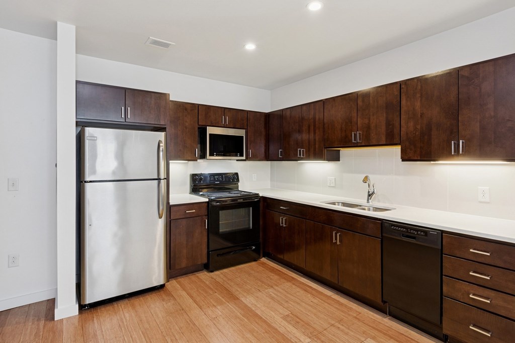 A kitchen with dark wood cabinets and a white counter top.