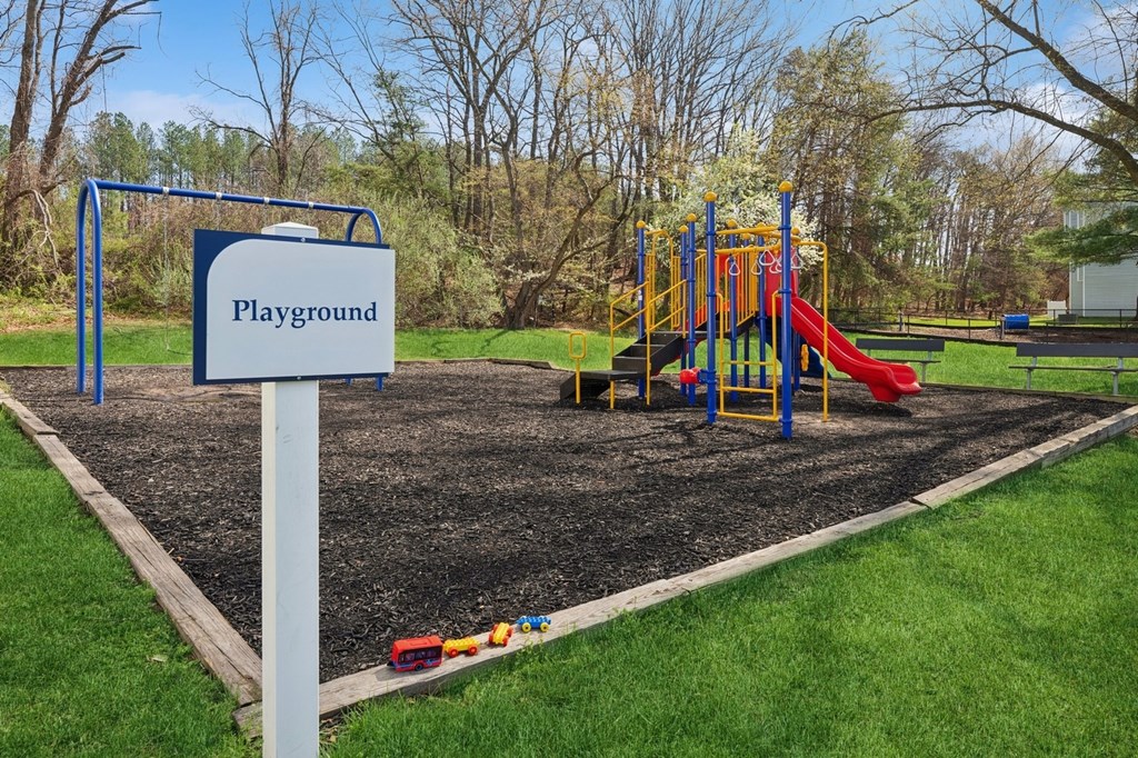 A playground with a red slide and a blue sign.