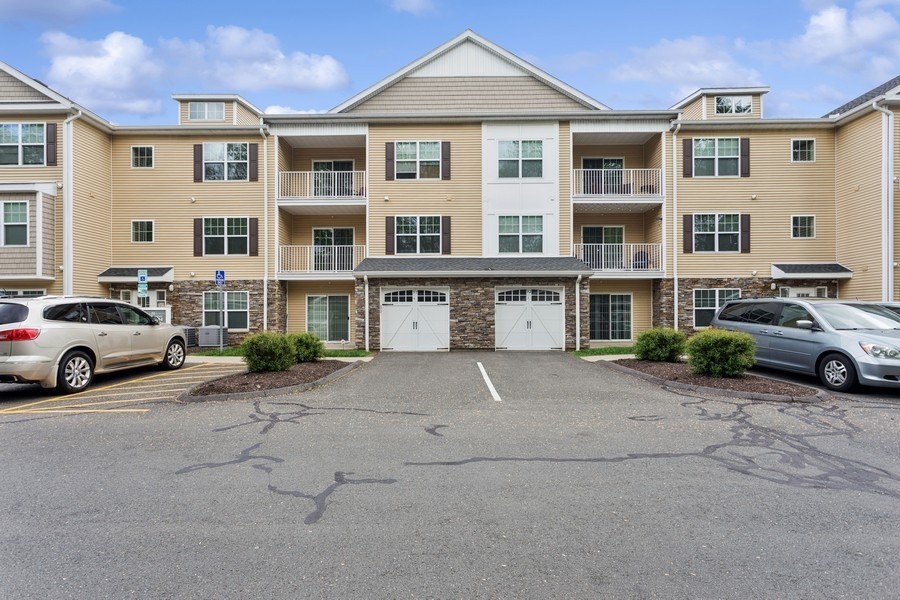 A parking lot in front of a large apartment building with two cars parked.