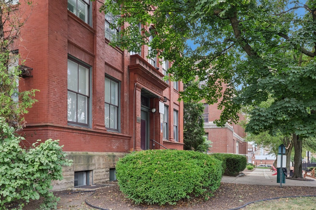 A red brick building with a green bush in front.