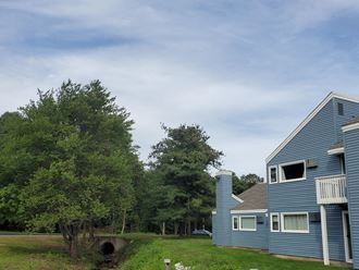 a blue house with a bridge in the foreground and trees in the background