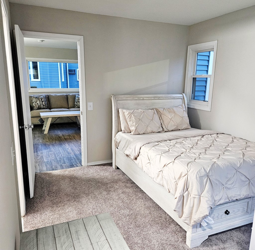 A bedroom with a large bed with a view to the living room