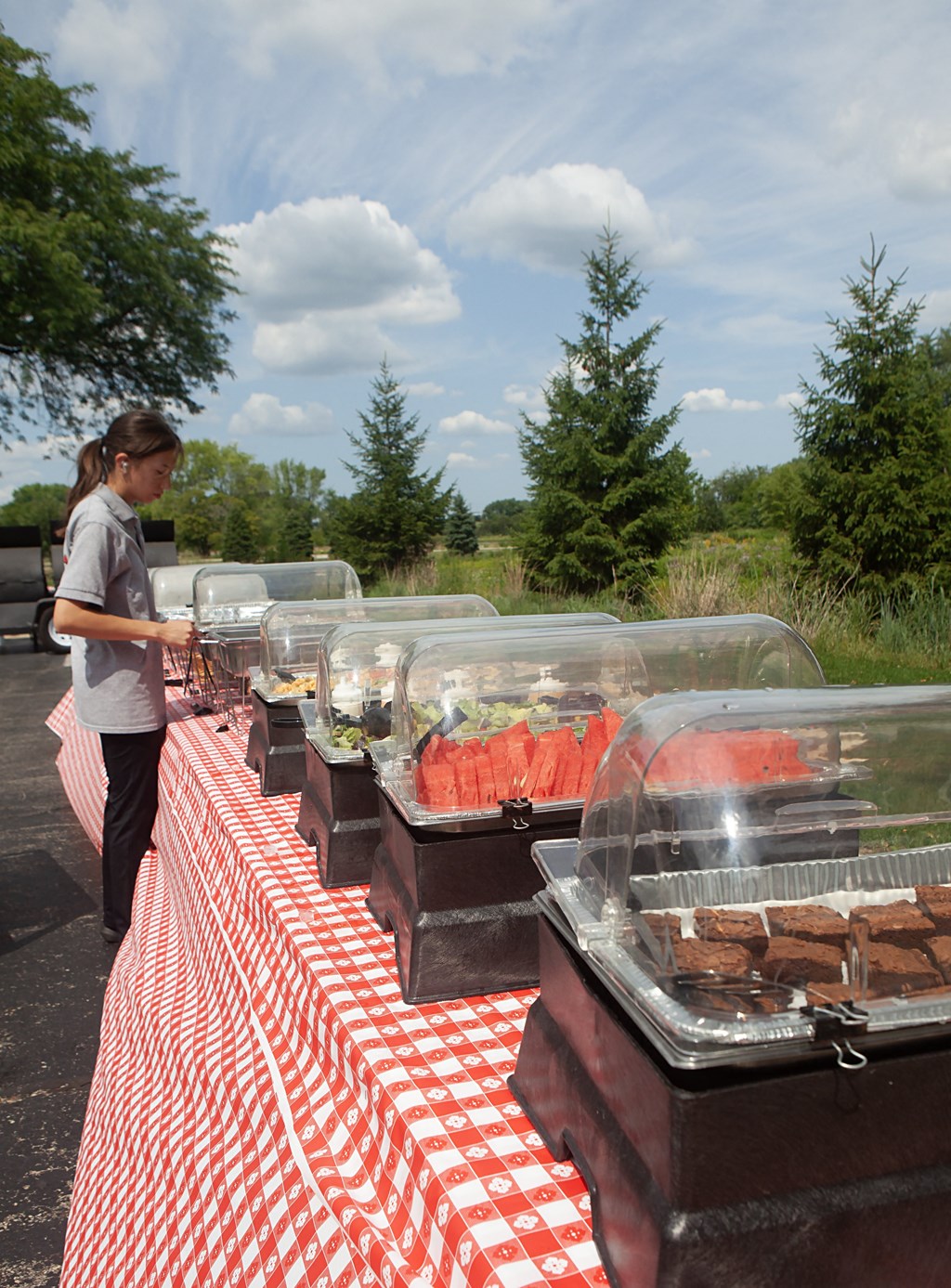 a woman is standing next to a table full of trays of food