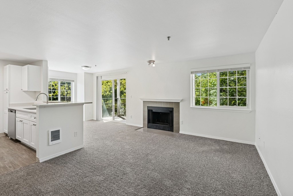 A spacious living room with a fireplace and a kitchen area.