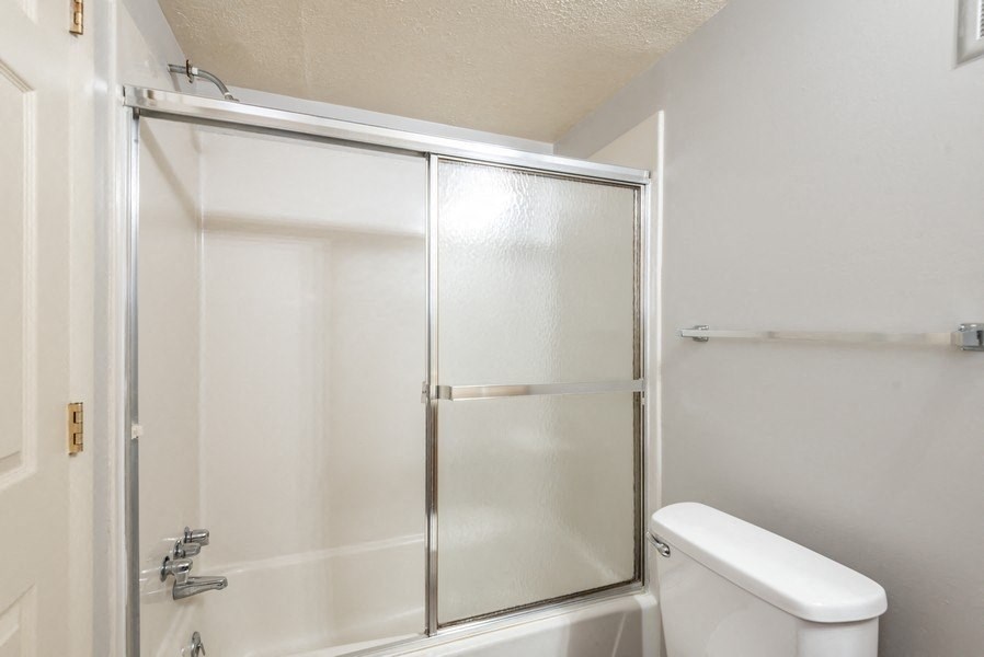 A white toilet sits next to a glass shower door in a bathroom.