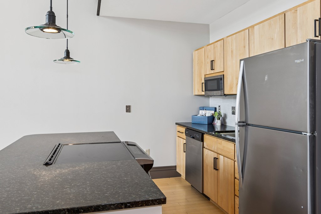 A kitchen with a black counter top and a black refrigerator.