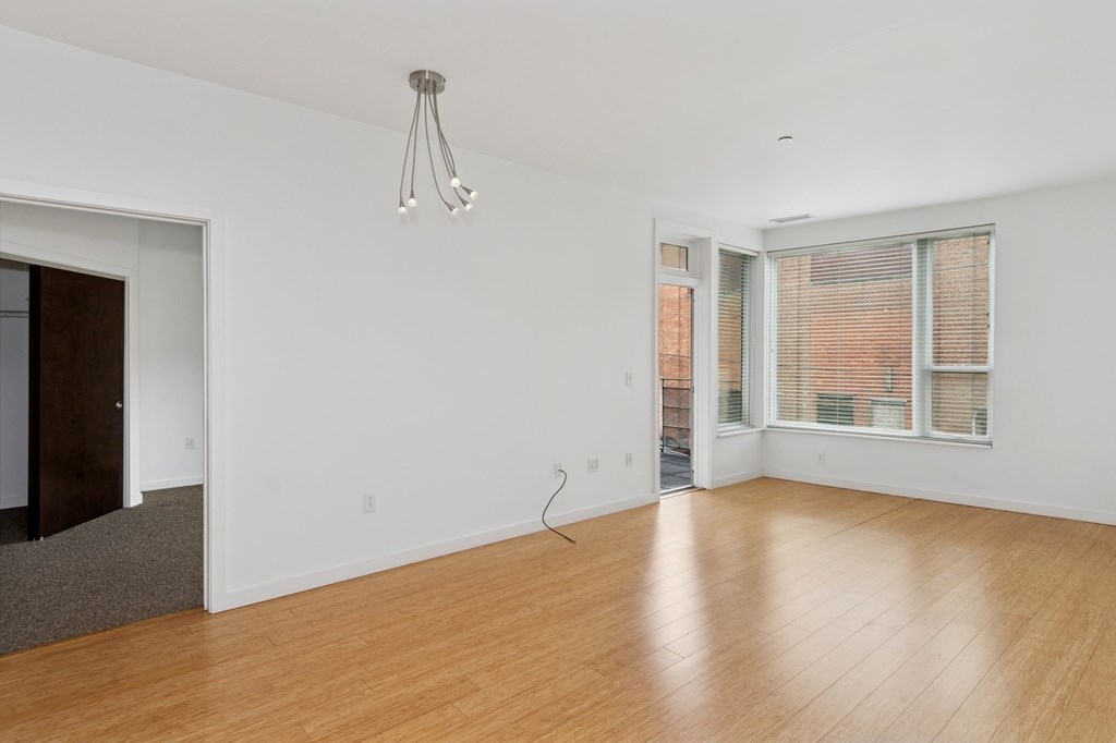 A room with wooden floors and a window with blinds.