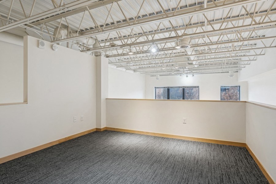 A room with a grey carpet and a white ceiling with a window.
