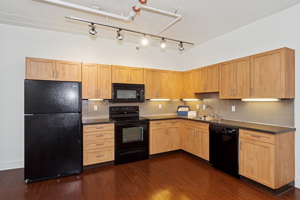 A kitchen with black appliances and wooden cabinets.