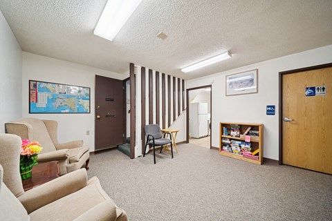 A living room with a couch, chair, and a small table with a vase of flowers on it.
